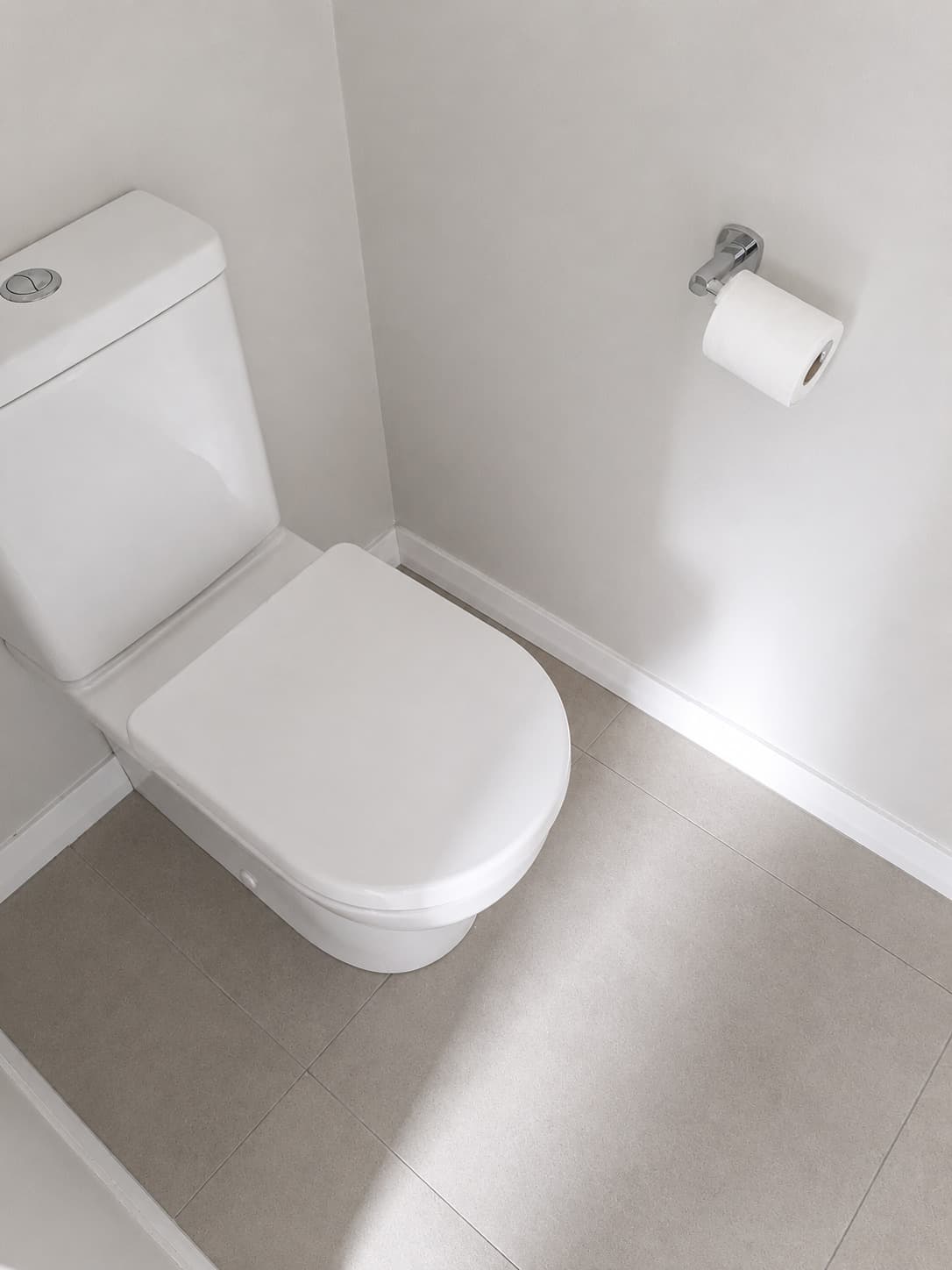 Renovated toilet room with white toilet suite and large-format floor tiles - Ambient Civil Auckland
