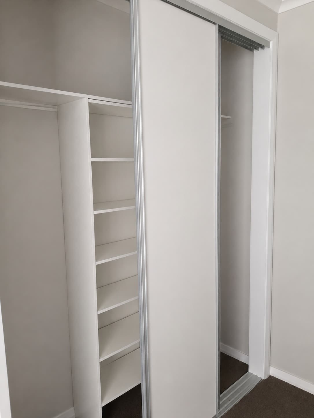 Built-in wardrobe interior with white melamine shelving and sliding doors - Ambient Civil Auckland