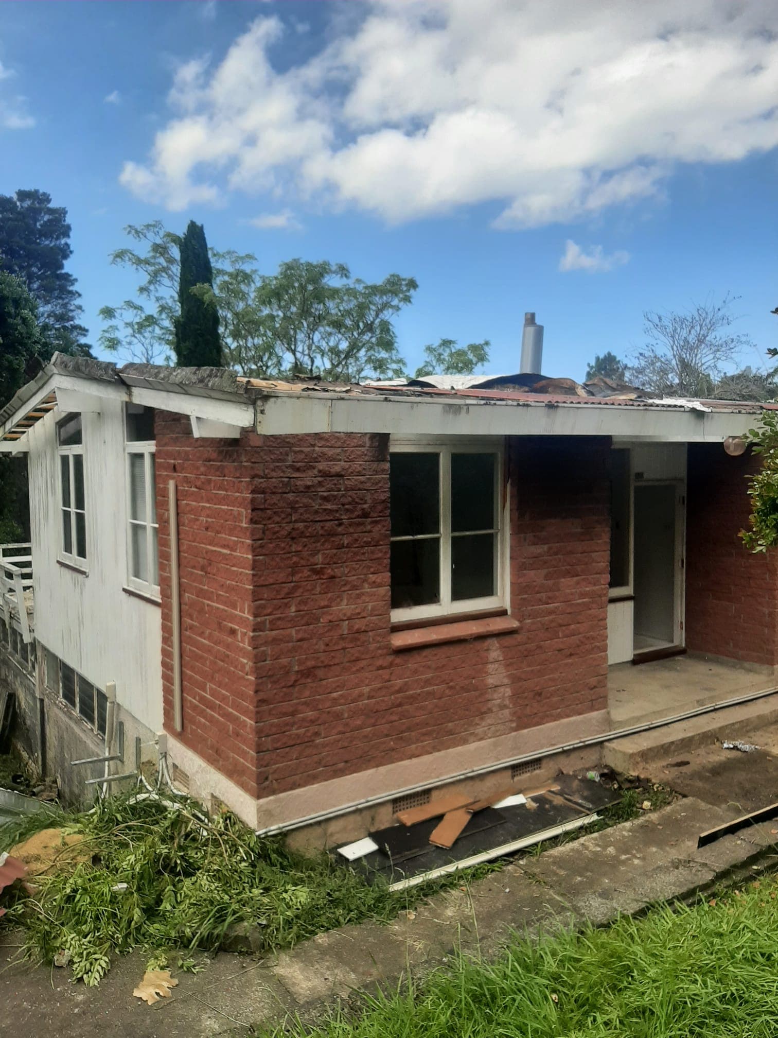 Brick house mid-demolition with roof partially removed and exterior stripped - Ambient Civil Auckland
