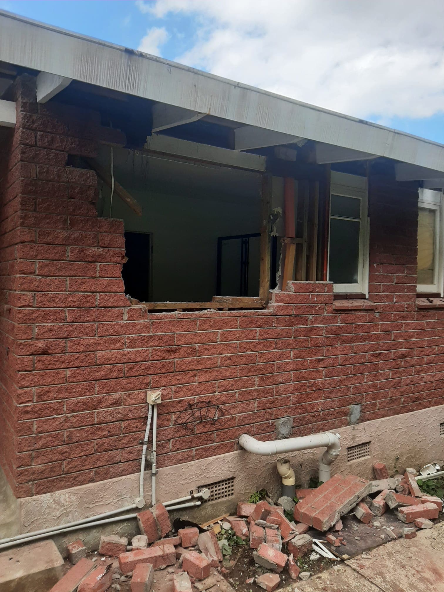 Brick house wall with window opening knocked out during residential demolition with rubble below - Ambient Civil Auckland