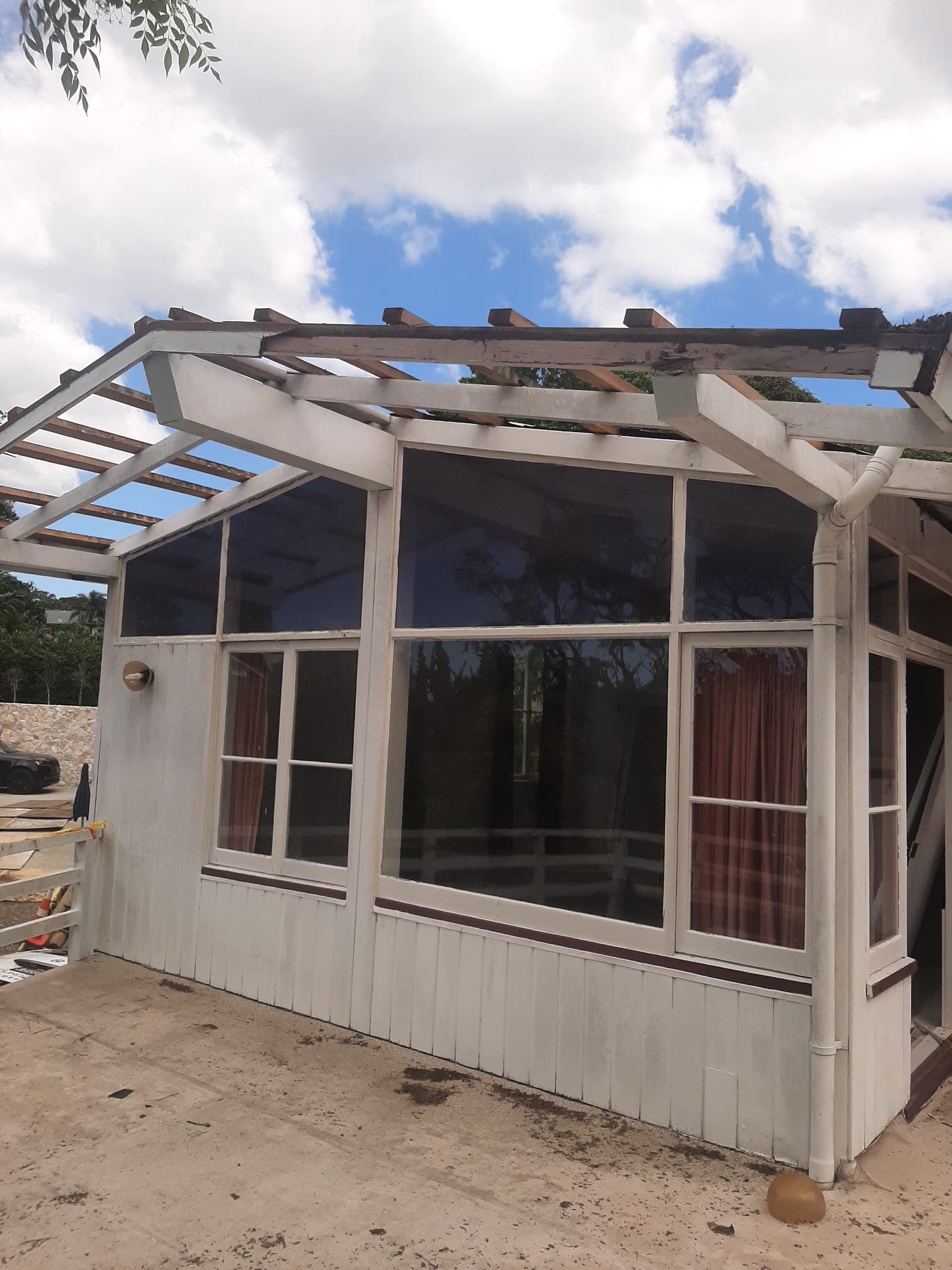 Weatherboard house sunroom with roof removed and exposed rafters during partial demolition - Ambient Civil Auckland