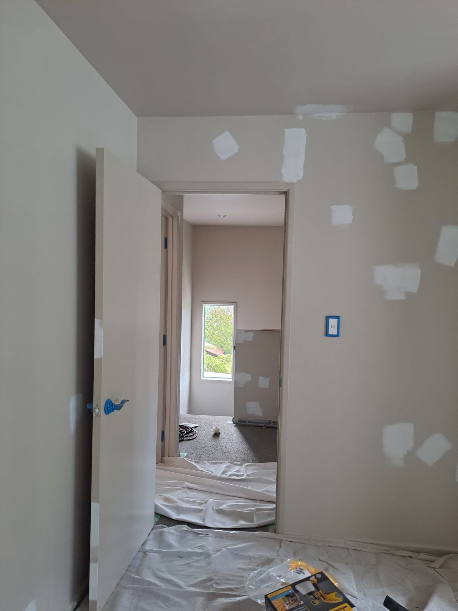 Hallway doorway with drop sheets and patched walls during paint preparation - Ambient Civil Auckland
