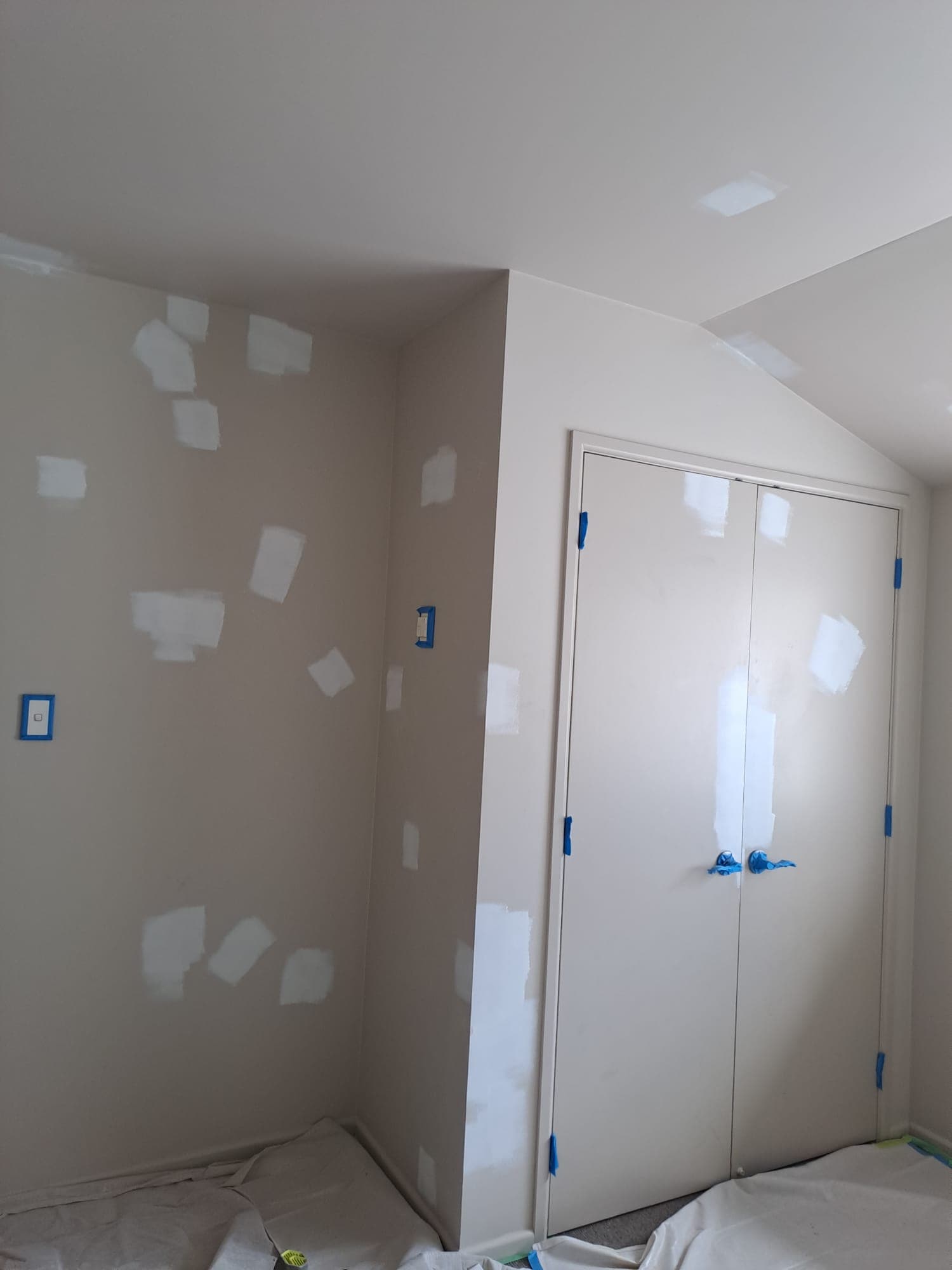 Bedroom wall with filler patches and masked wardrobe doors prepared for repaint with drop sheets down - Ambient Civil Auckland