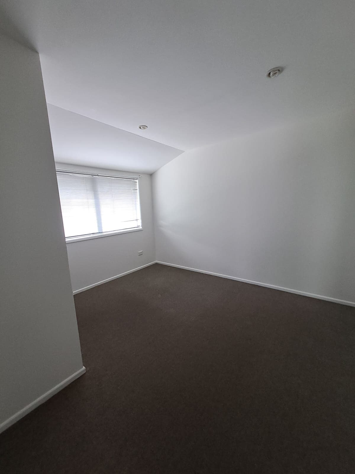 Small bedroom with freshly painted white walls and dark carpet after interior repaint - Ambient Civil Auckland