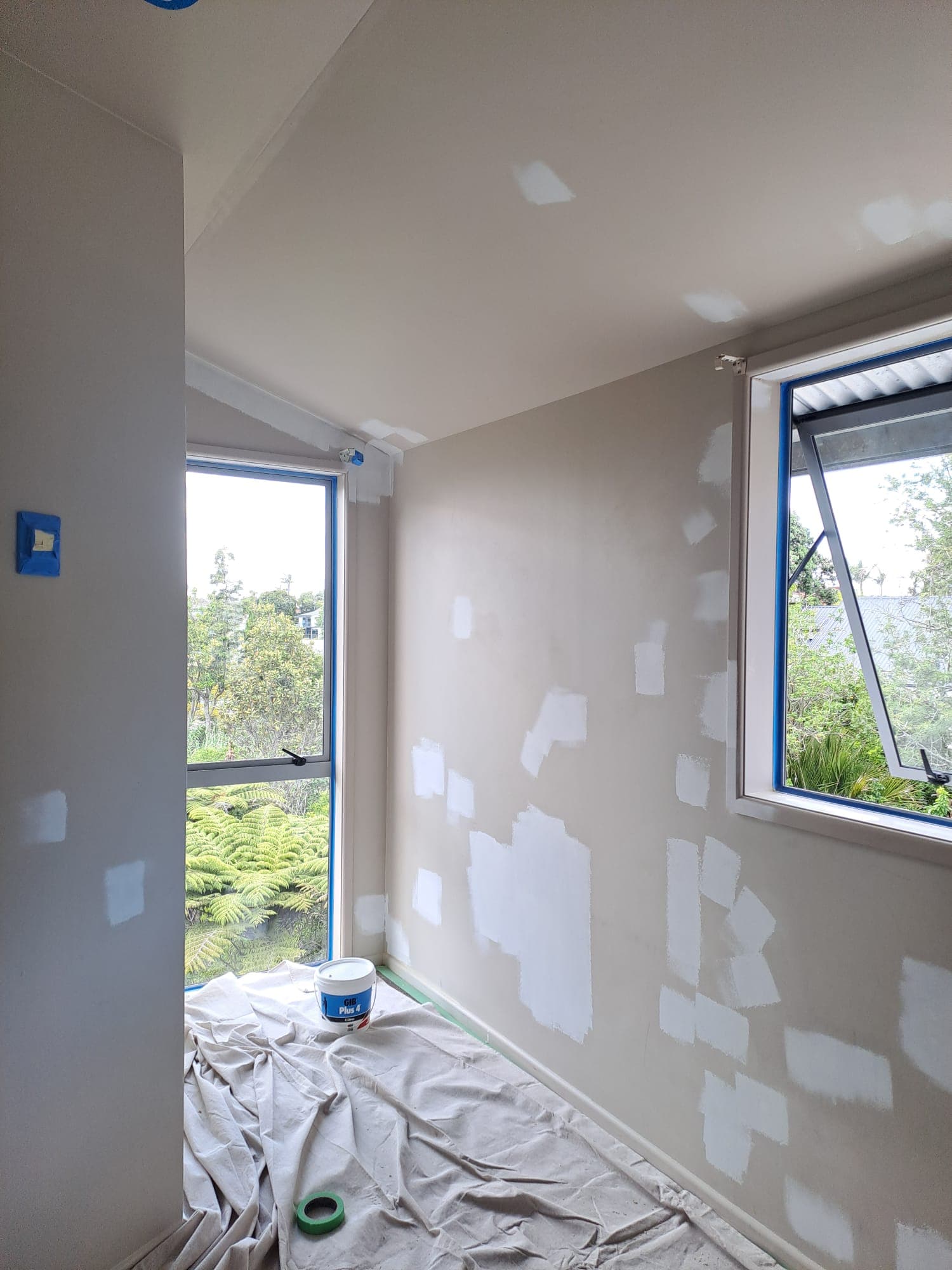 Corner room with patched walls and masked windows prepped for painting - Ambient Civil Auckland