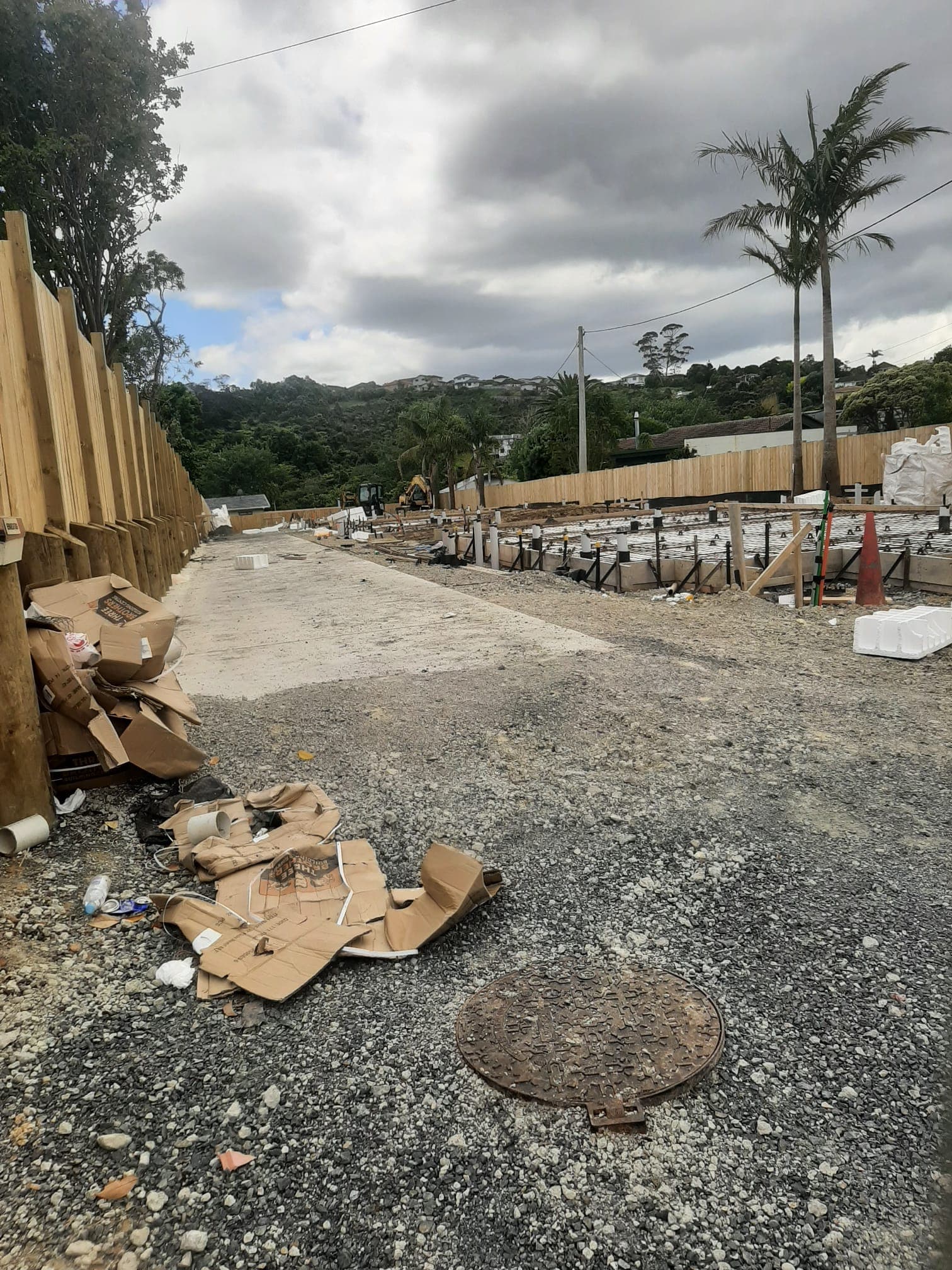 Timber pole retaining wall and fence beside gravel site access at a residential build - Ambient Civil Auckland