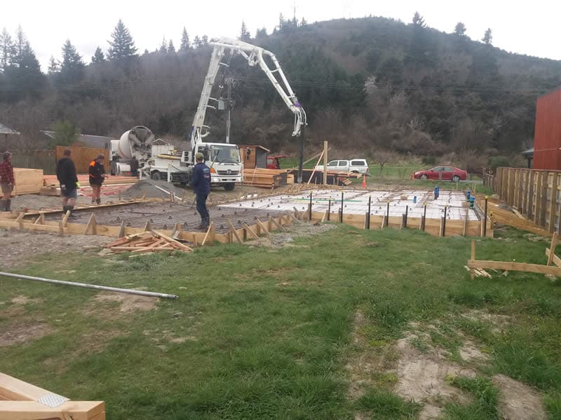 Concrete pump truck pouring a reinforced house foundation slab with timber formwork - Ambient Civil Auckland