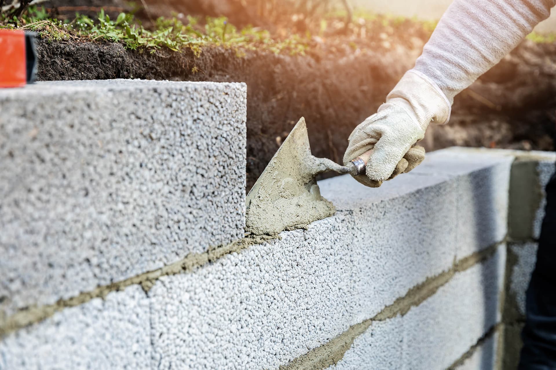 Bricklayer troweling mortar onto a concrete block wall - Ambient Civil Auckland