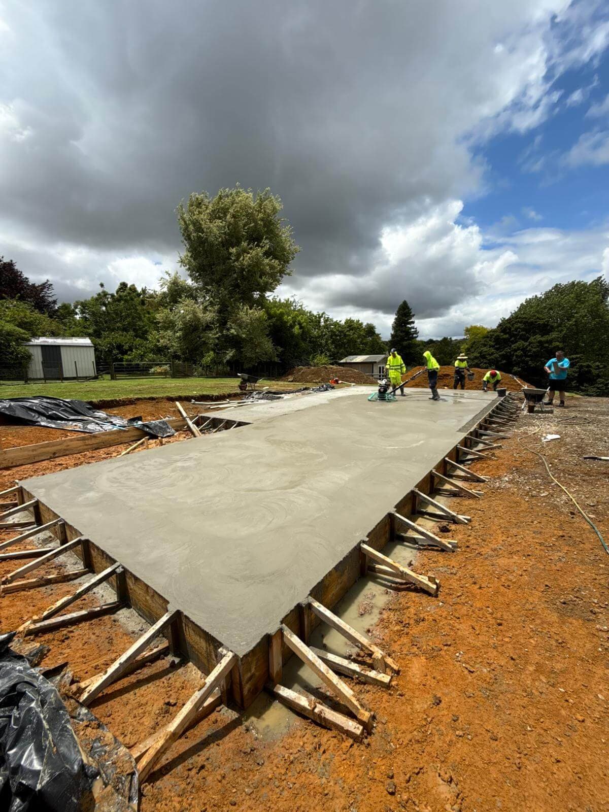 Crew floating a large freshly poured concrete foundation slab - Ambient Civil Auckland
