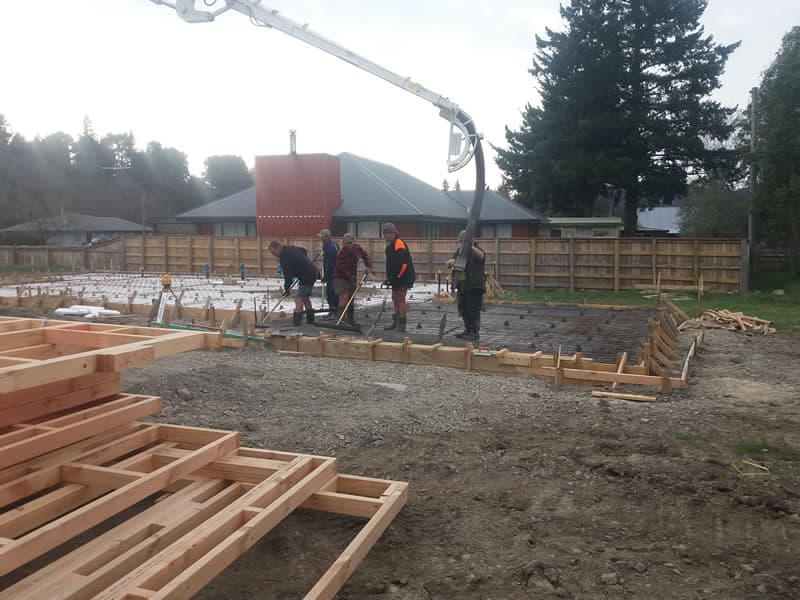 Construction crew pouring and screeding a reinforced concrete foundation slab - Ambient Civil Auckland
