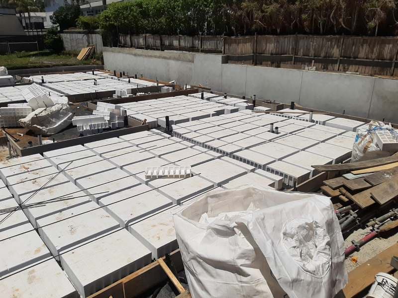 Waffle-pod raft slab foundation with steel reinforcing alongside concrete retaining wall - Ambient Civil Auckland