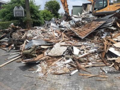 Excavator demolishing Parnell commercial building with debris pile - Ambient Civil Auckland
