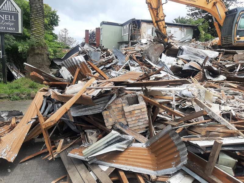 Excavator demolishing a building with timber and iron rubble in Auckland - Ambient Civil Auckland