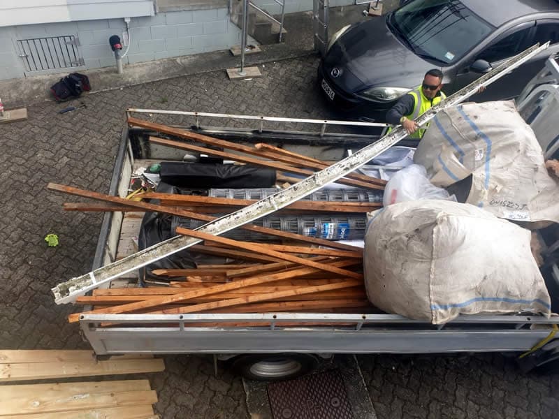 Worker loading demolition debris onto a trailer - Ambient Civil Auckland