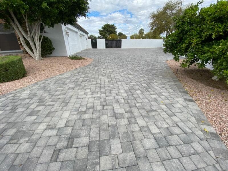 Large grey paver driveway sweeping toward a white house - Ambient Civil Auckland