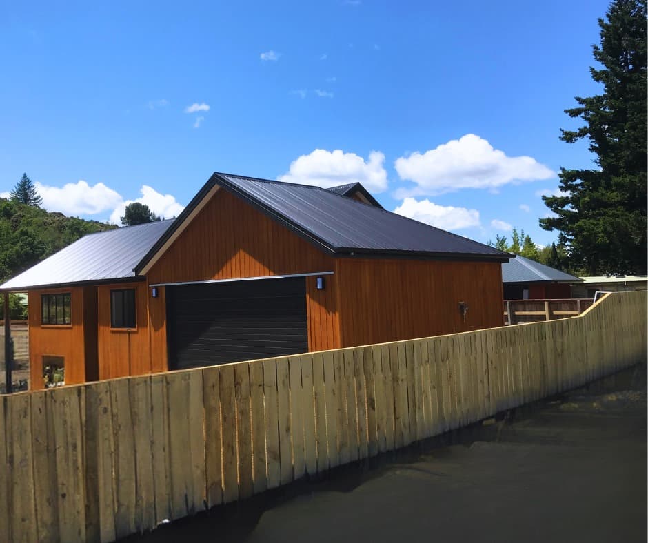 New timber paling boundary fence beside completed timber-clad building - Ambient Civil Auckland