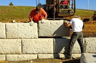 Workers placing large interlocking concrete blocks for a retaining wall - Ambient Civil Auckland