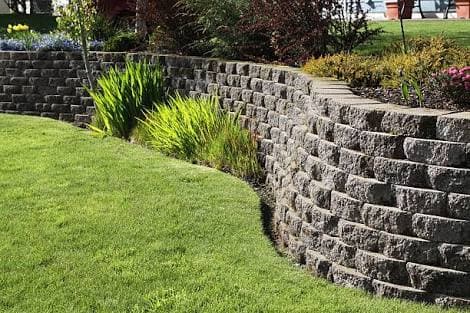 Curved segmental block retaining wall in a landscaped Auckland garden - Ambient Civil Auckland