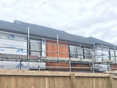 New house under construction with scaffolding and timber boundary fence - Ambient Civil Auckland