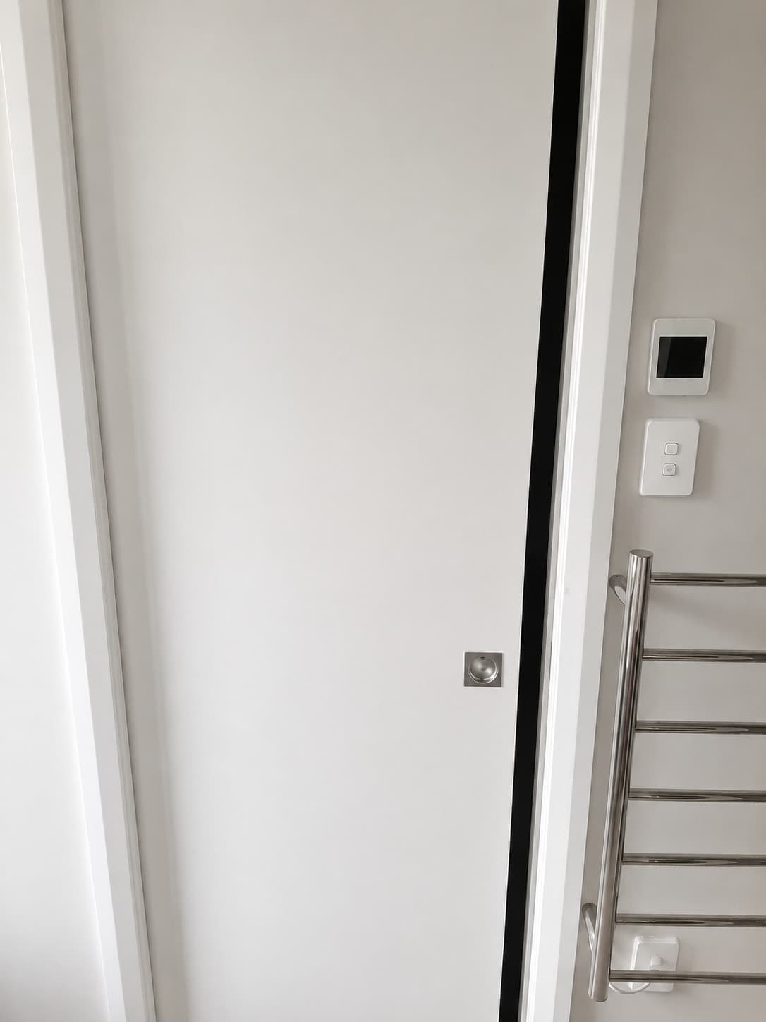 Finished bathroom cavity slider door switch panel and heated towel rail - Ambient Civil Auckland