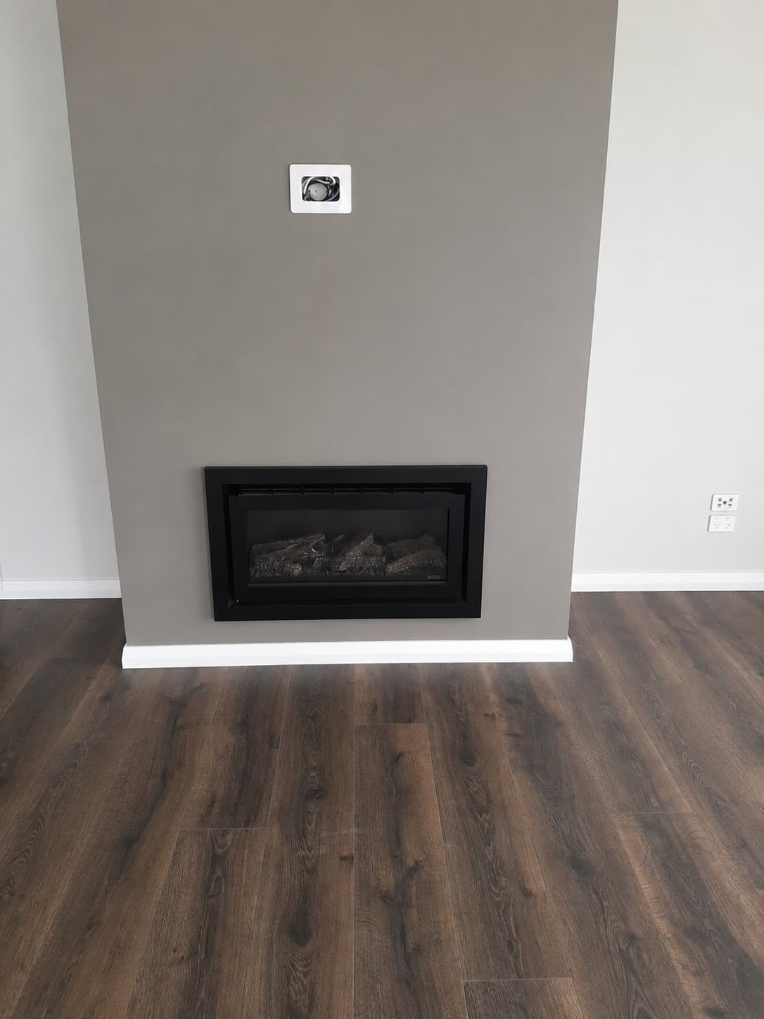 Renovated living room with inset gas fireplace, grey feature wall and dark timber flooring - Ambient Civil Auckland