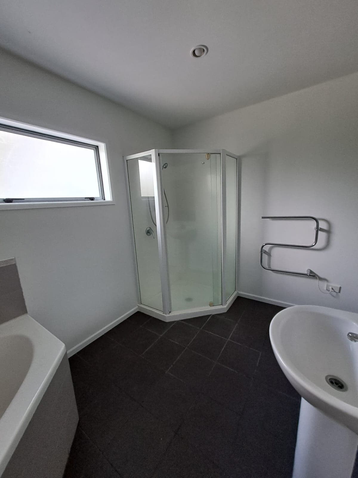 Finished bathroom with corner glass shower heated towel rail and pedestal basin after painting - Ambient Civil Auckland