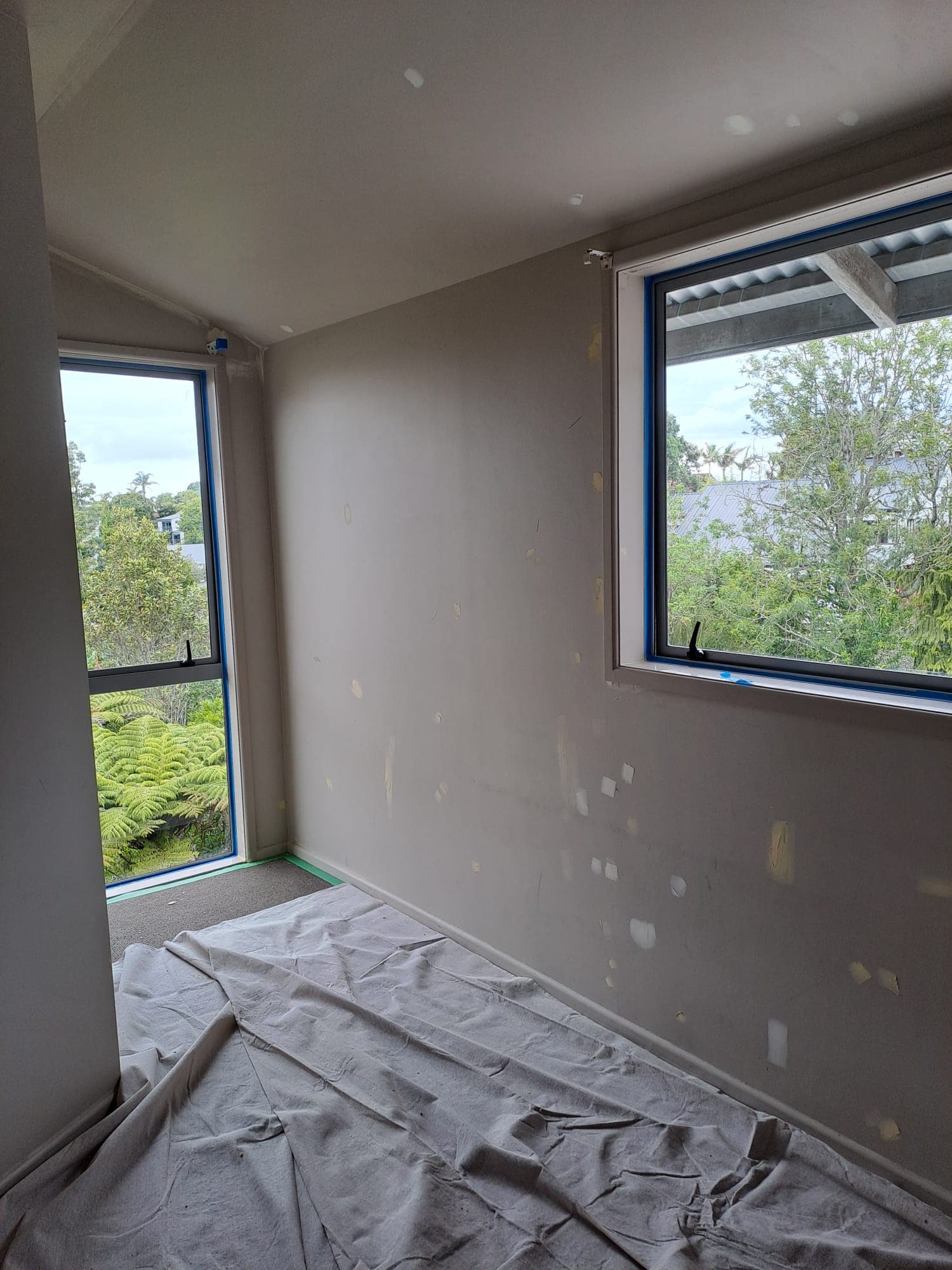 Bedroom wall patching and filler prep beside masked windows - Ambient Civil Auckland