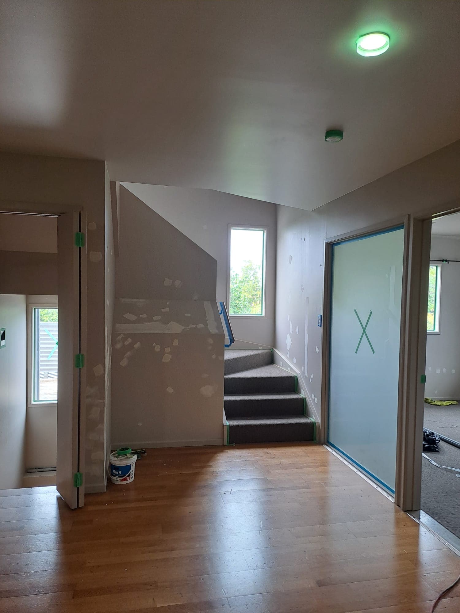 Entry and staircase area with patched walls and masked fittings during interior repaint - Ambient Civil Auckland