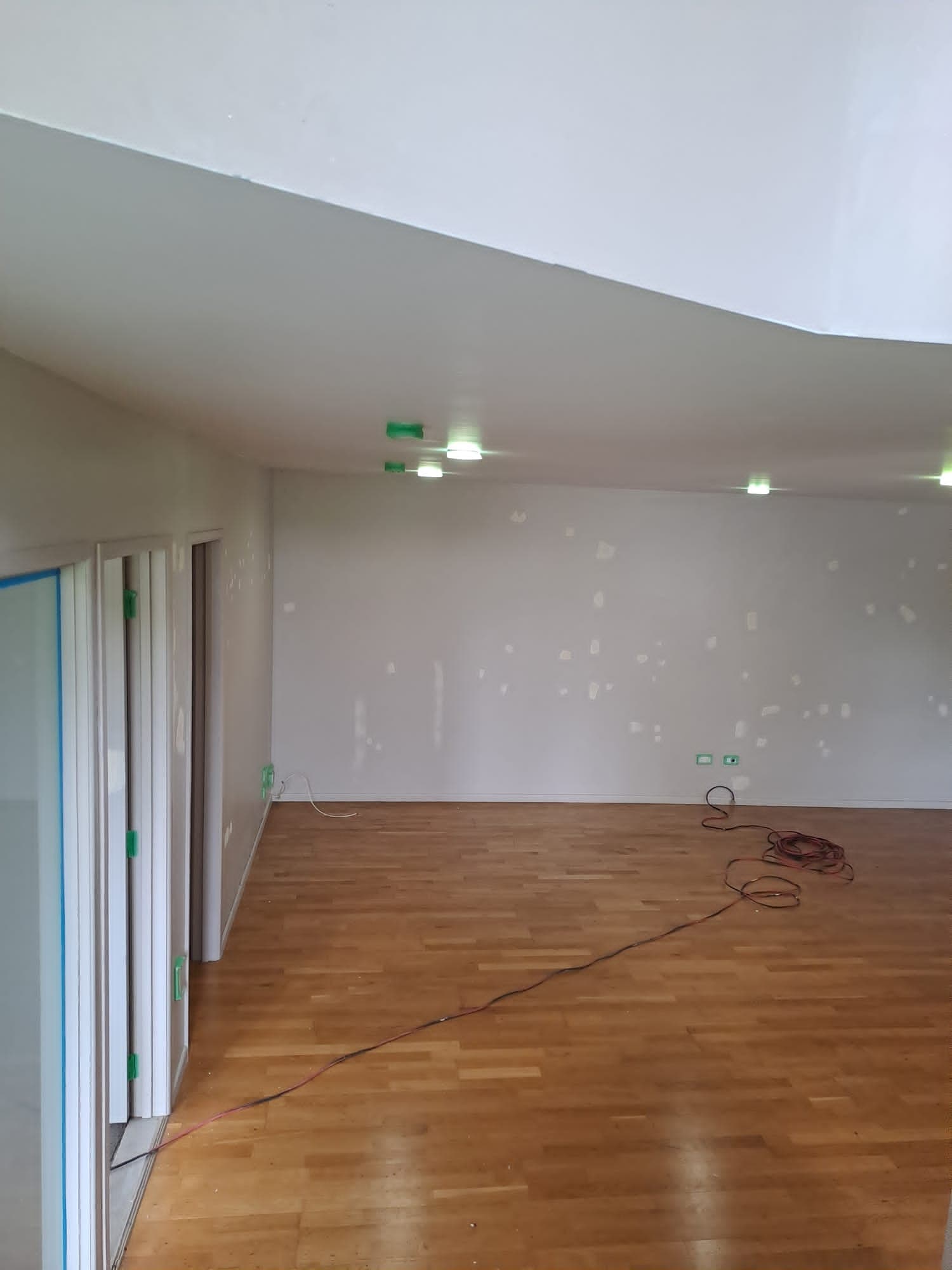 Empty living room with timber floor and patched feature wall during interior repaint - Ambient Civil Auckland