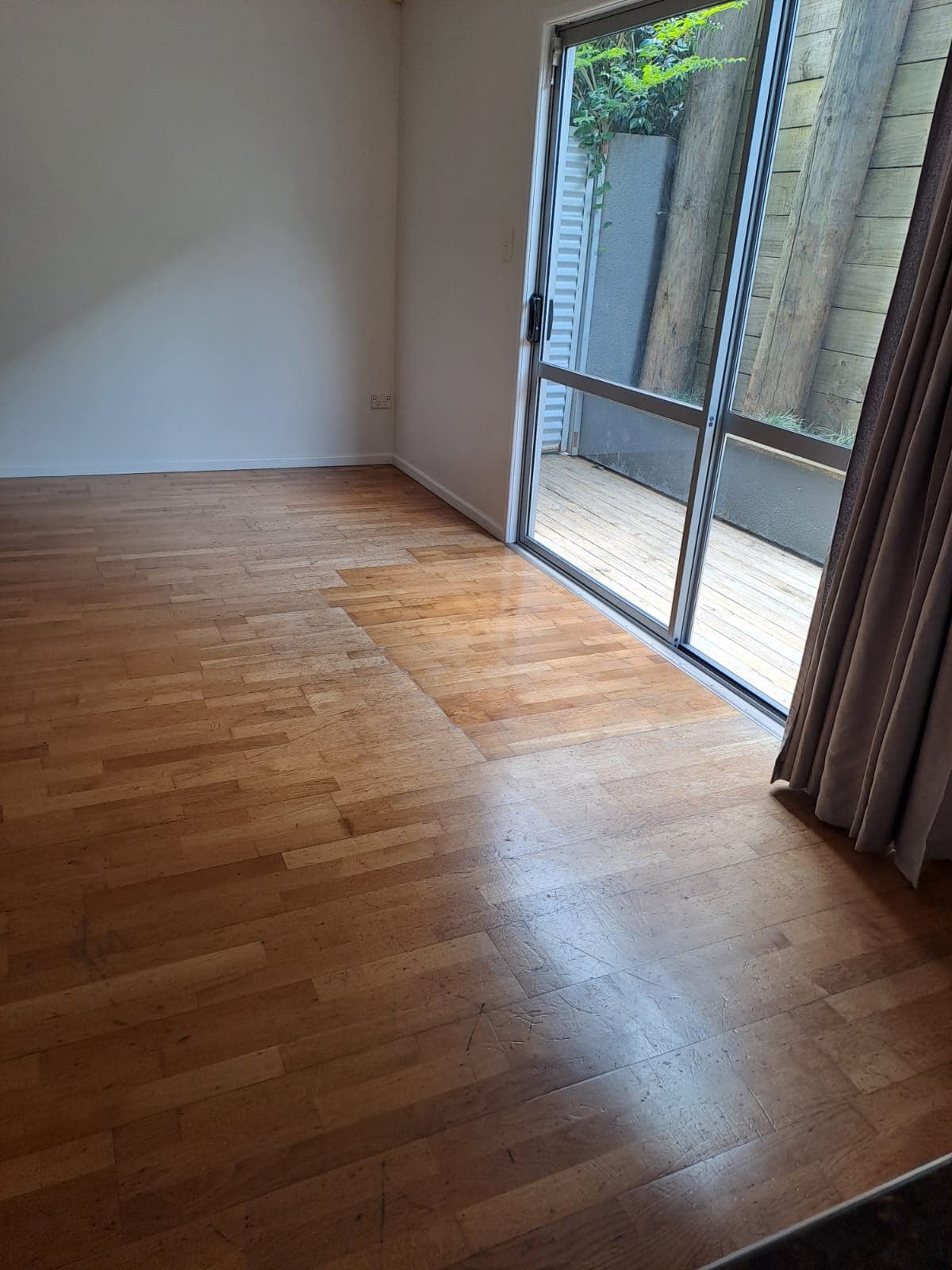 Finished living room with timber floor and sliding door to deck after interior repaint - Ambient Civil Auckland