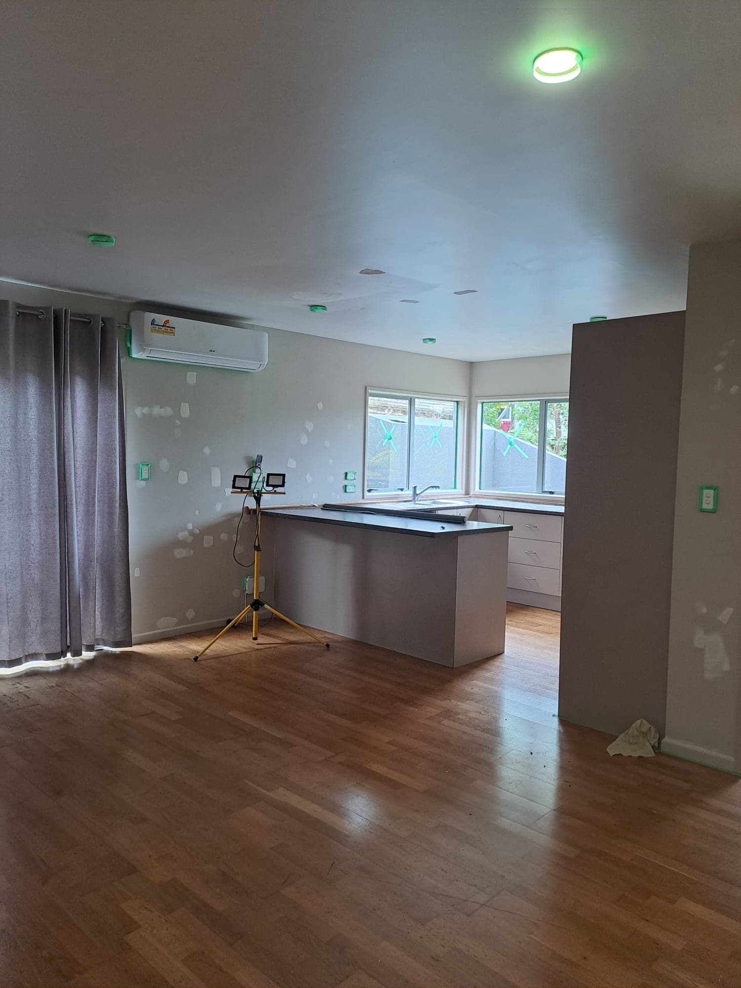 Open-plan kitchen and living area with peninsula bench and patched walls during interior repaint - Ambient Civil Auckland