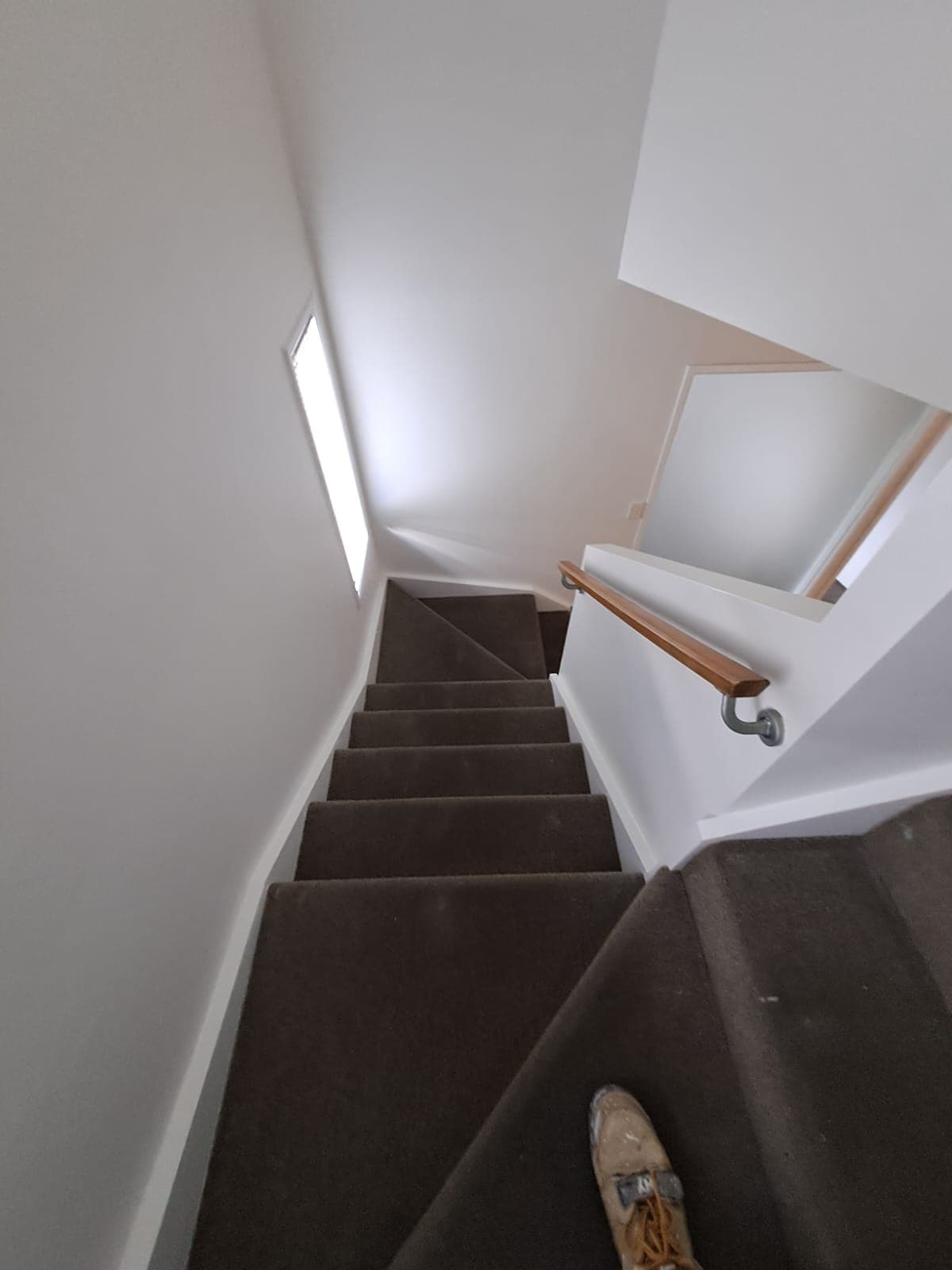 Carpeted staircase with freshly painted white walls and timber handrail - Ambient Civil Auckland