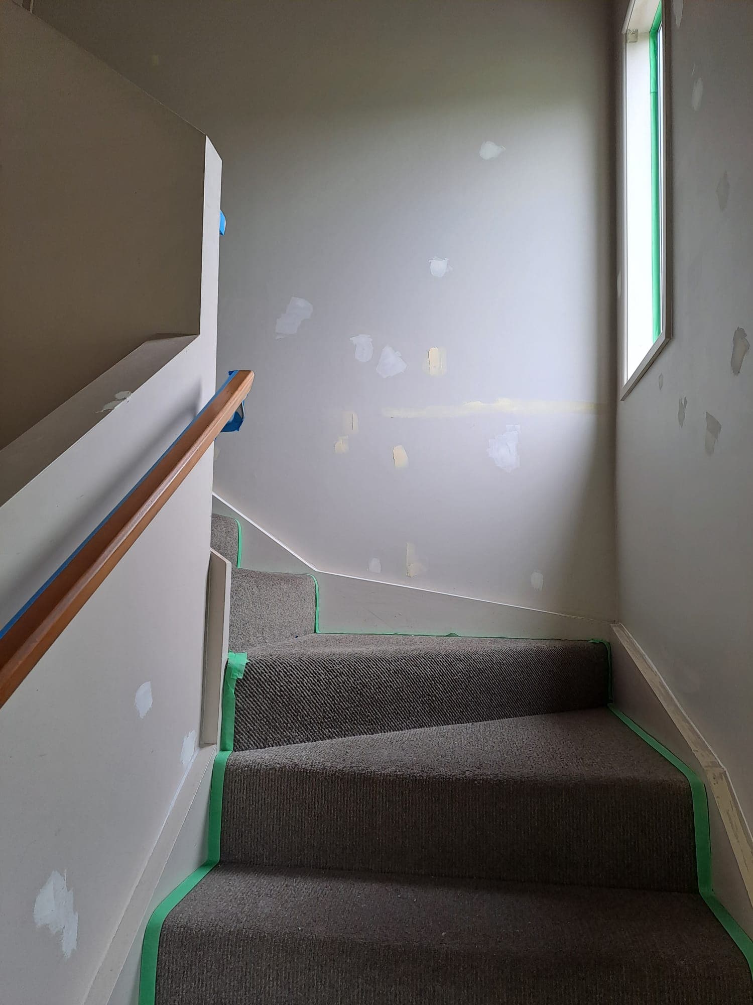 Stair landing wall paint preparation with filler patches and masking tape - Ambient Civil Auckland