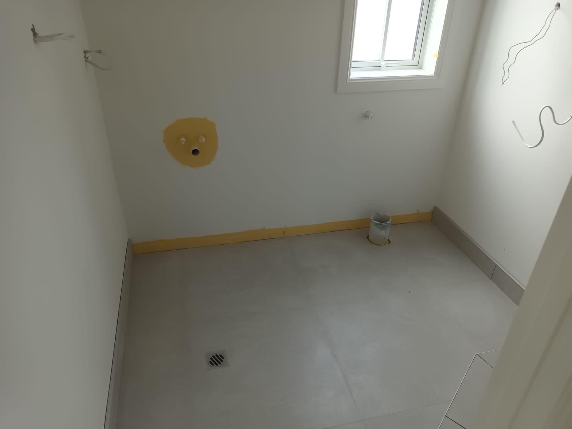 New-build bathroom with freshly tiled floor, floor drain and roughed-in plumbing during fit-out - Ambient Civil Auckland